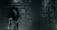 a woman standing in front of a blackboard with writing on it