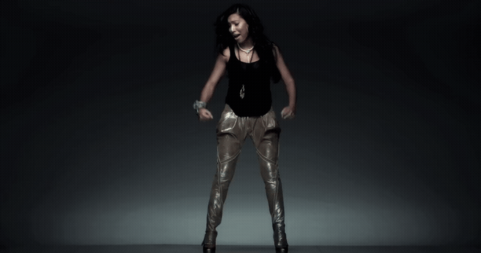 a woman standing in a dark room with her hands on her hips