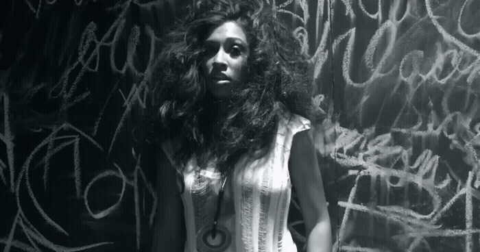 a woman standing in front of a wall covered in graffiti