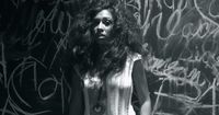 a woman standing in front of a wall covered in graffiti