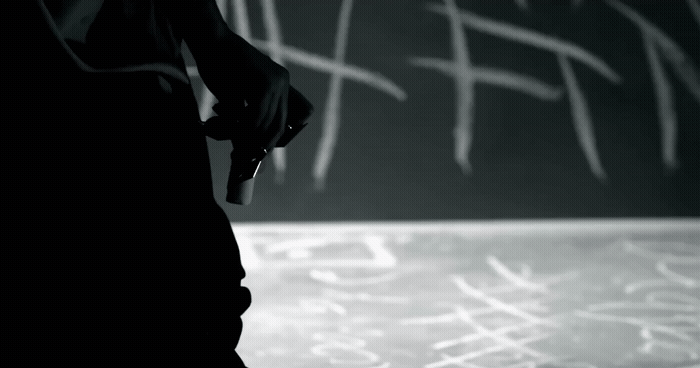 a black and white photo of someone writing on a chalkboard