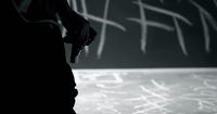 a black and white photo of someone writing on a chalkboard