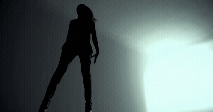 a woman standing in the shadows of a room