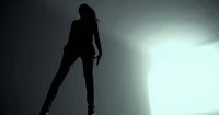 a woman standing in the shadows of a room
