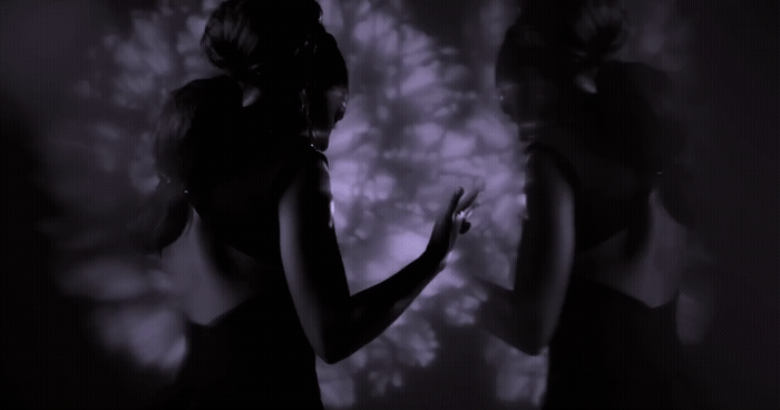 a woman standing in front of a wall in a dark room