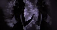 a woman standing in front of a wall in a dark room