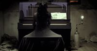 a woman sitting at a piano in a dark room
