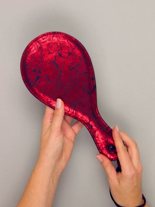 a person holding a red paddle over a gray background