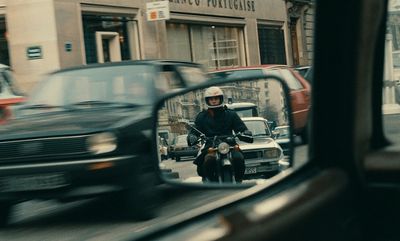 a man riding a motorcycle in front of a car