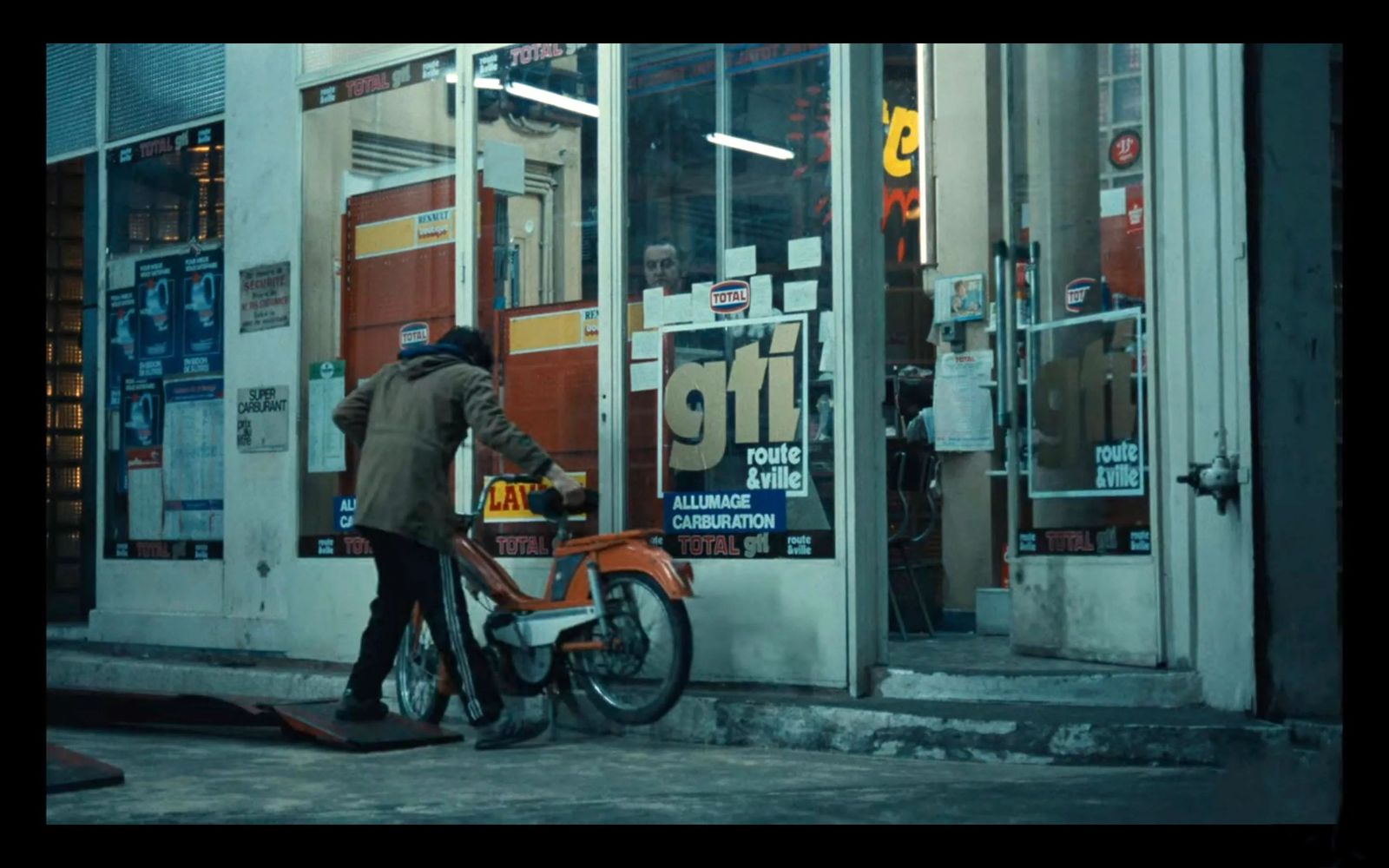 a man standing next to a parked motorcycle in front of a store