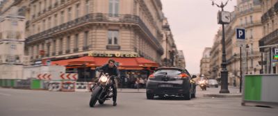 a man riding a motorcycle down a street next to a car