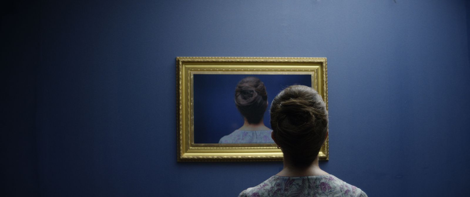 a woman standing in front of a painting of a woman's head