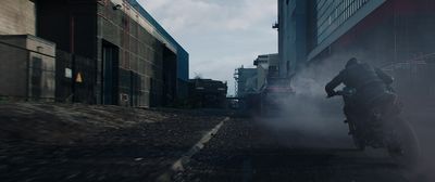 a man riding a motorcycle down a street next to tall buildings