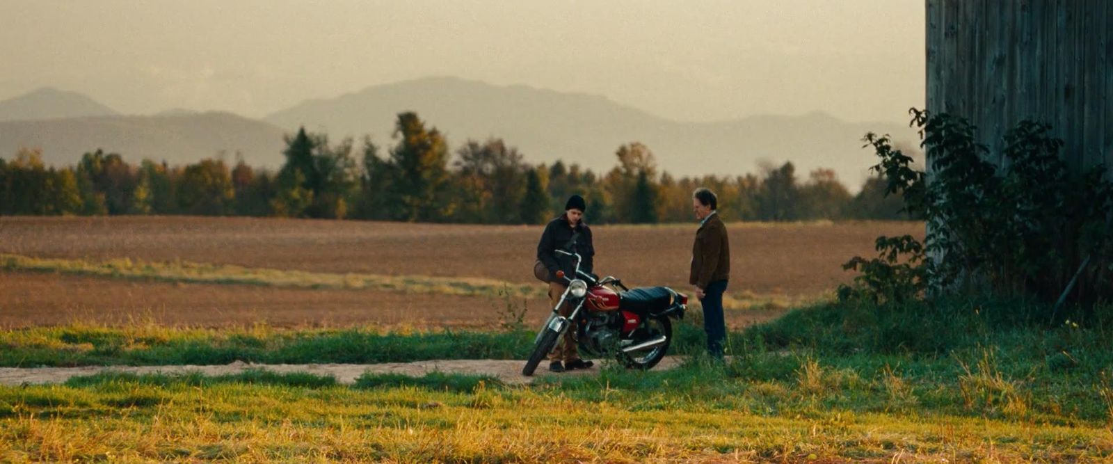 a couple of men standing next to a motorcycle