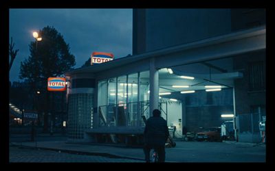 a man walking past a gas station at night