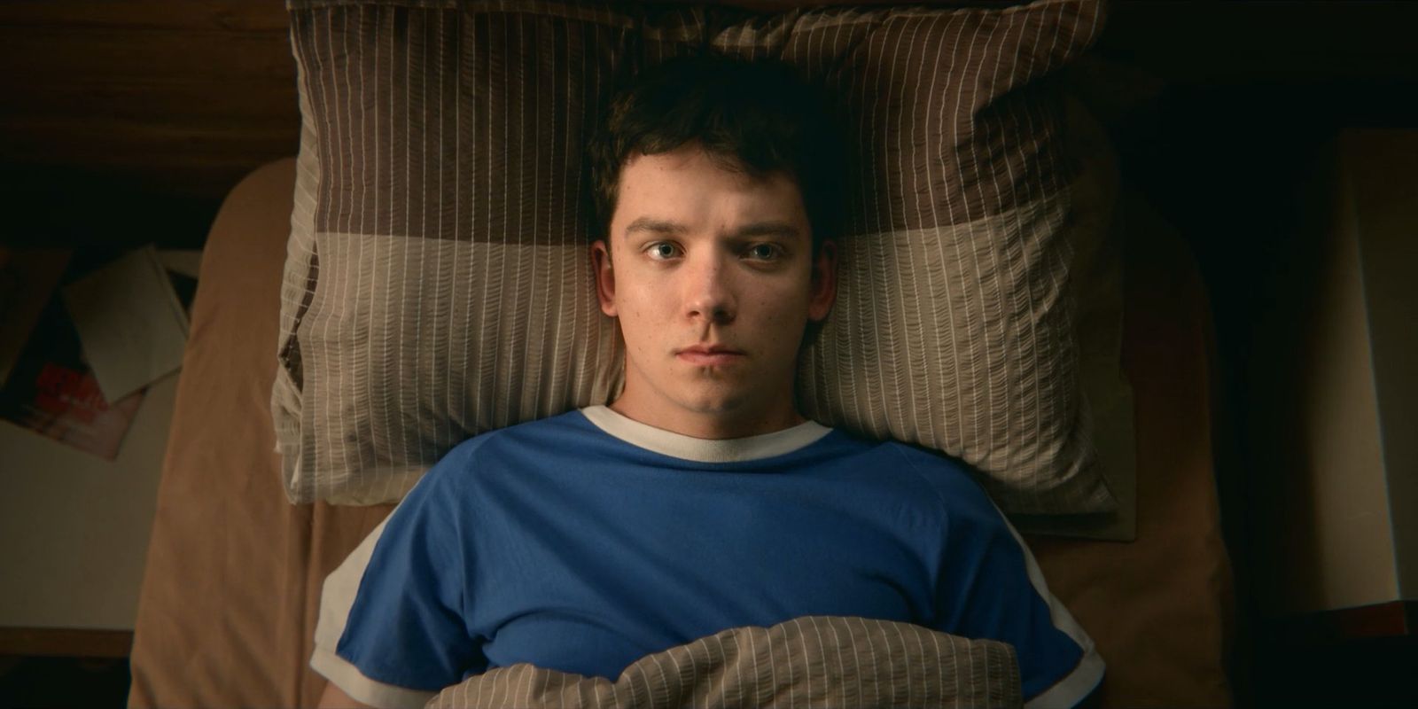 a young man laying in bed with a pillow