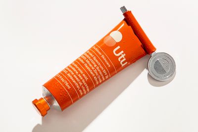 a tube of sunscreen next to a coin