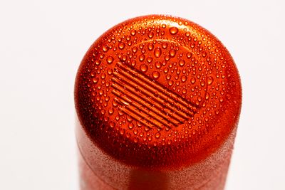 a close up of a red bottle with water drops on it