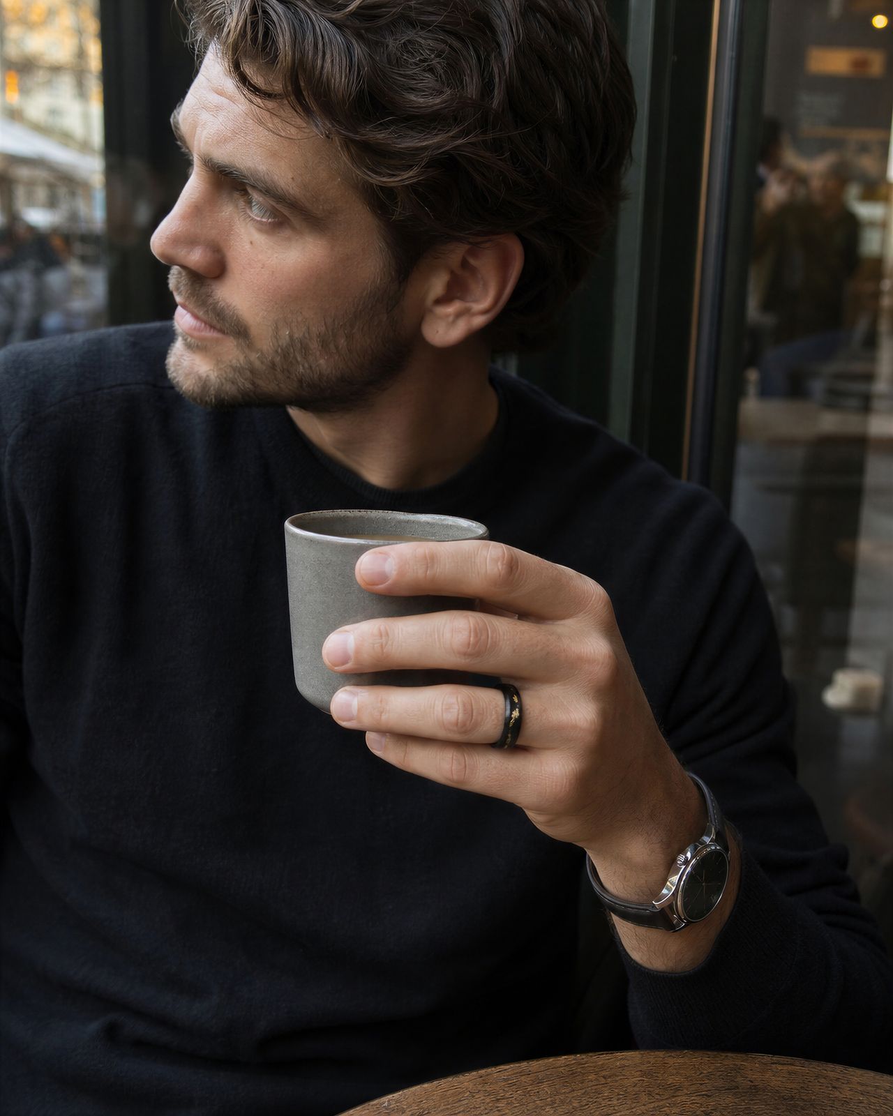 a man sitting at a table holding a cup of coffee
