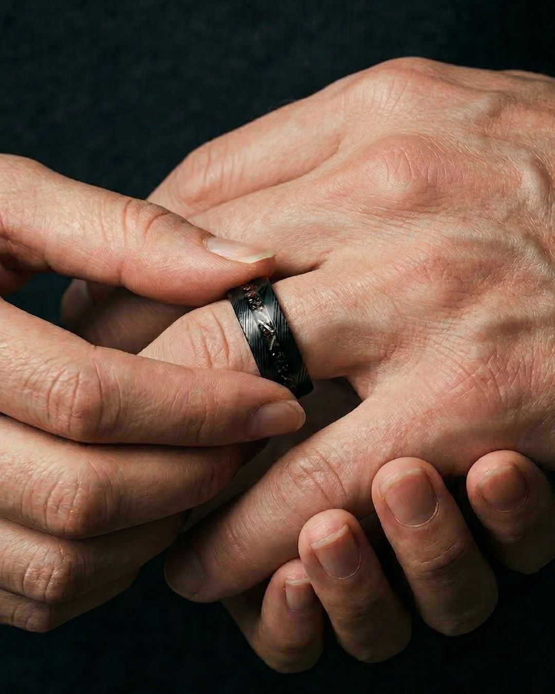 a man wearing a black ring with a skull on it