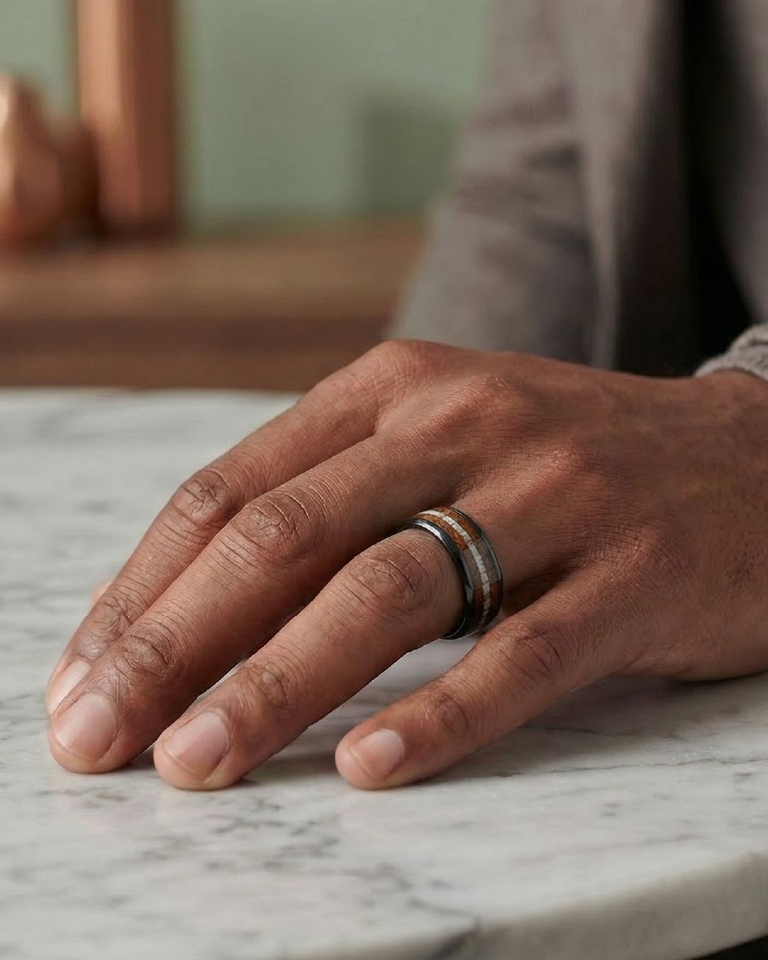 a man's hand with a wedding ring on a marble table