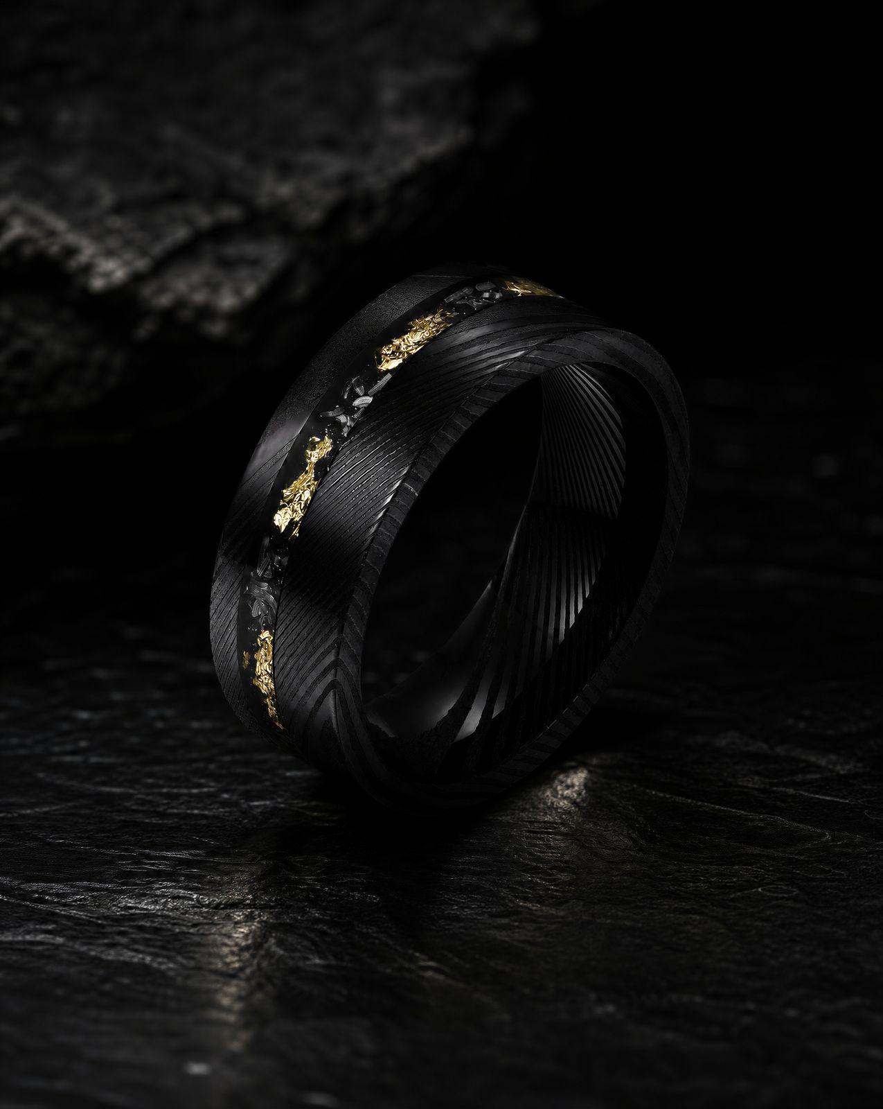 a black and gold wedding ring on a black surface