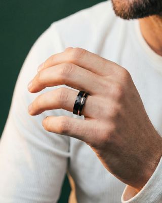 a man in a white shirt holding a black ring