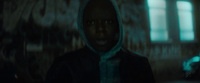 a man in a hooded jacket standing in a dark room