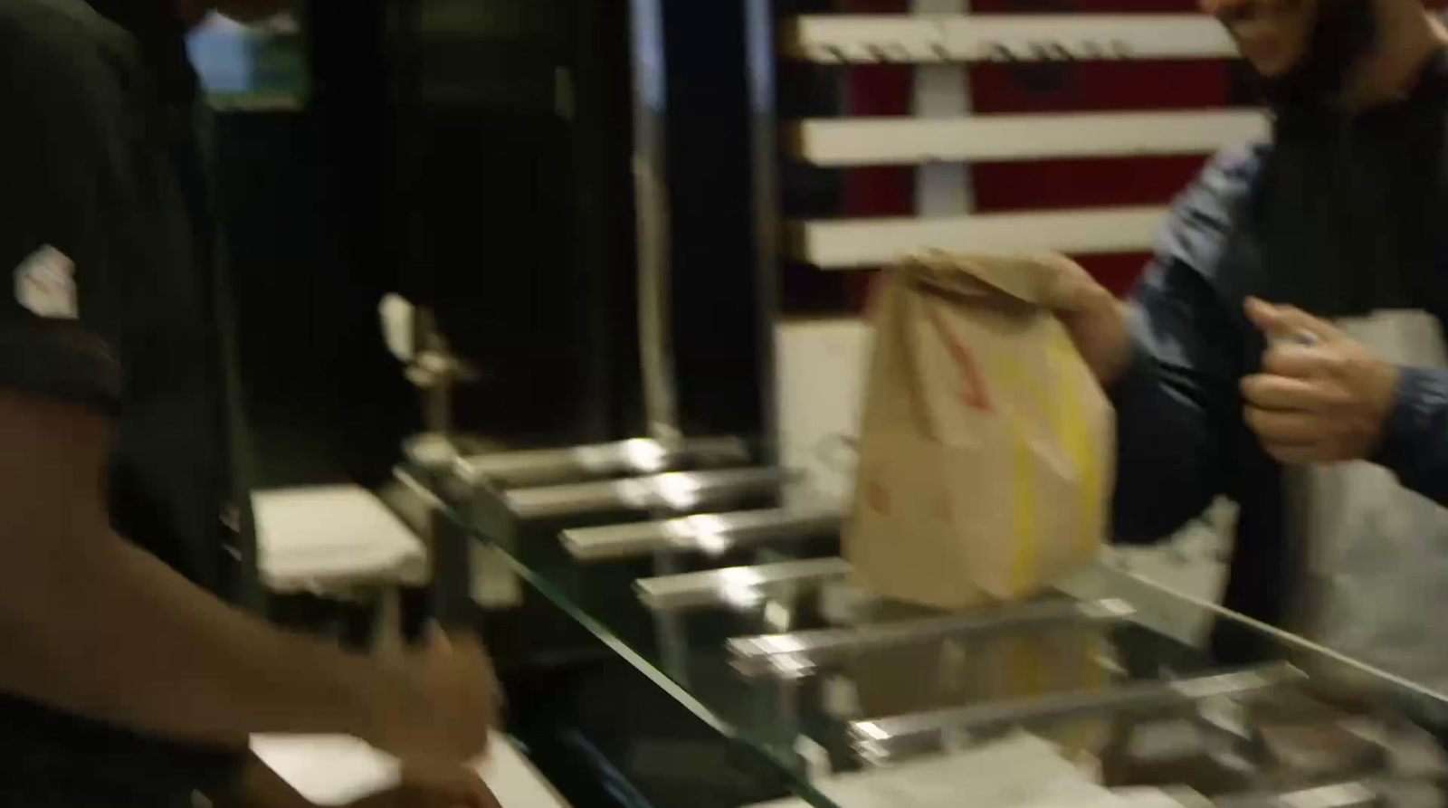 a man holding a paper bag in front of a counter