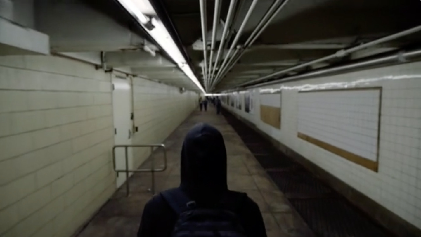 a person in a hooded jacket walking down a hallway