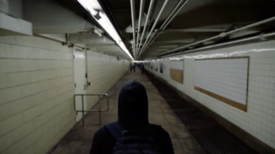 a person in a hooded jacket walking down a hallway