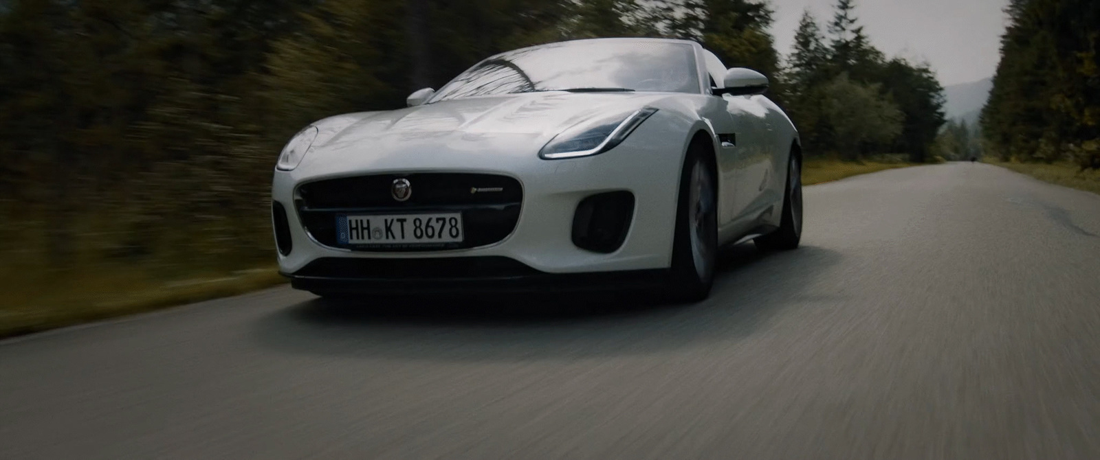 a white sports car driving down a road