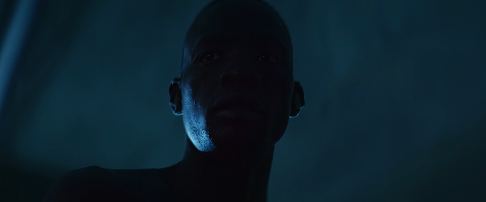 a man standing in a dark room with a blue light on his face