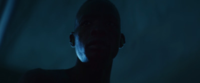 a man standing in a dark room with a blue light on his face