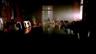 a dark room with a long table and chairs