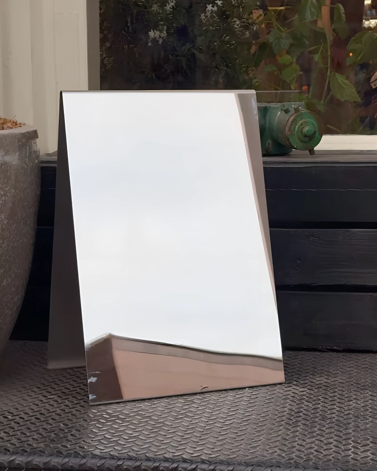 a mirror sitting on top of a table next to a potted plant