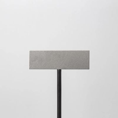 a square metal object on a black stand