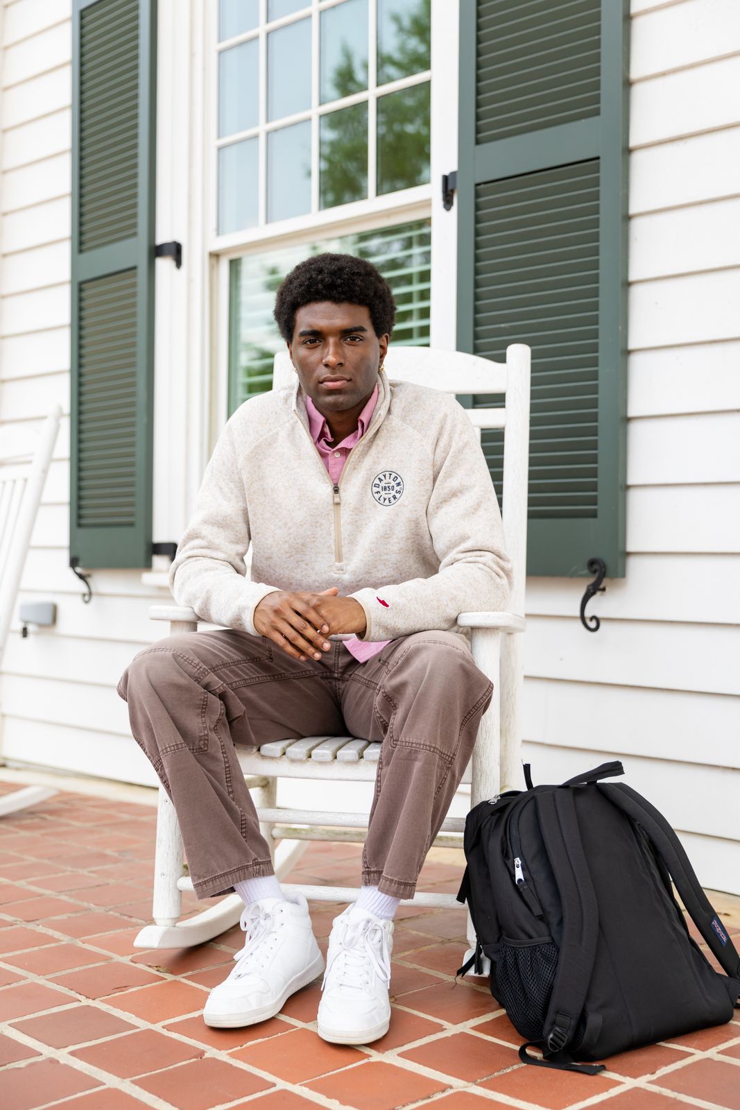 a man sitting on a white chair next to a backpack