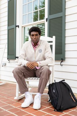 a man sitting on a white chair next to a backpack
