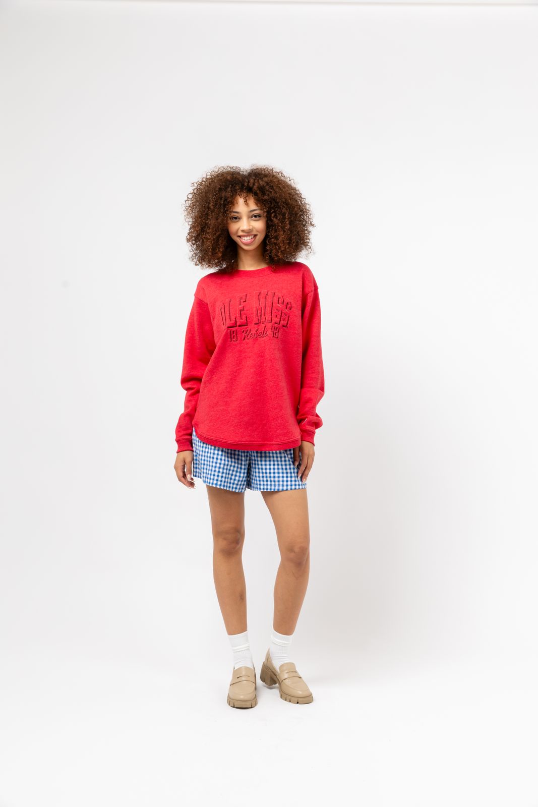 a woman wearing a red sweater and blue shorts