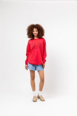 a woman wearing a red sweater and blue shorts