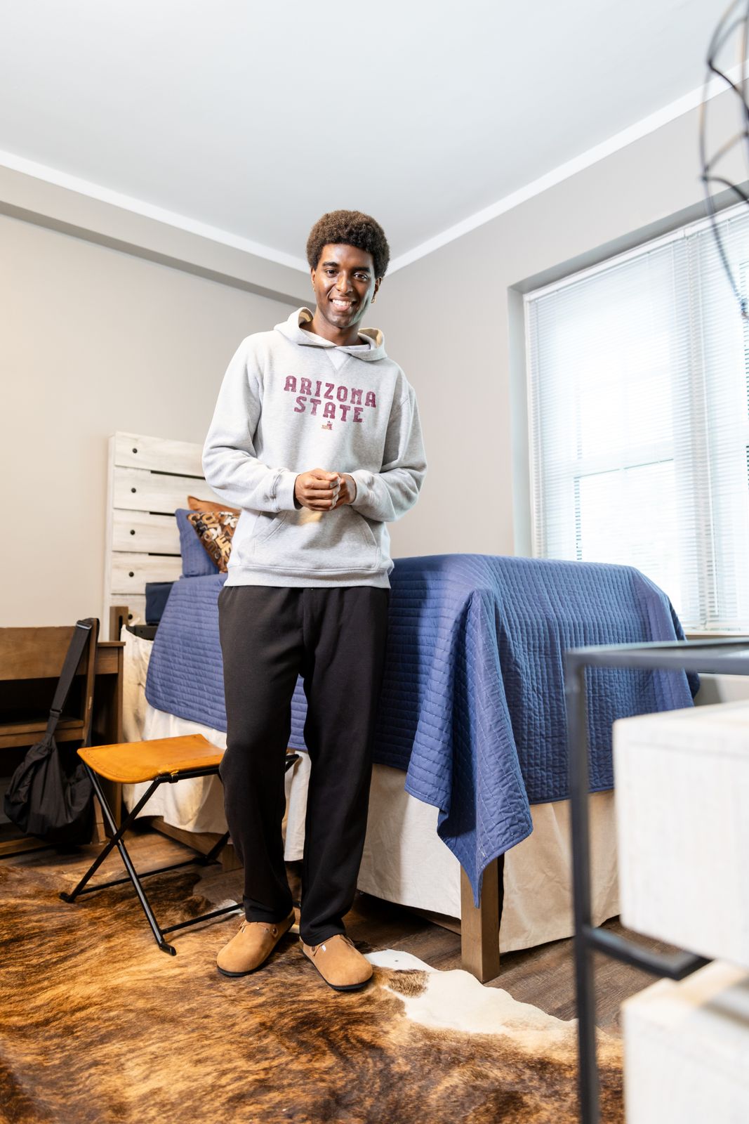 a man standing next to a bed in a bedroom