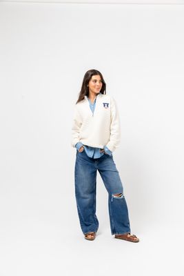 a woman standing in a white sweater and jeans