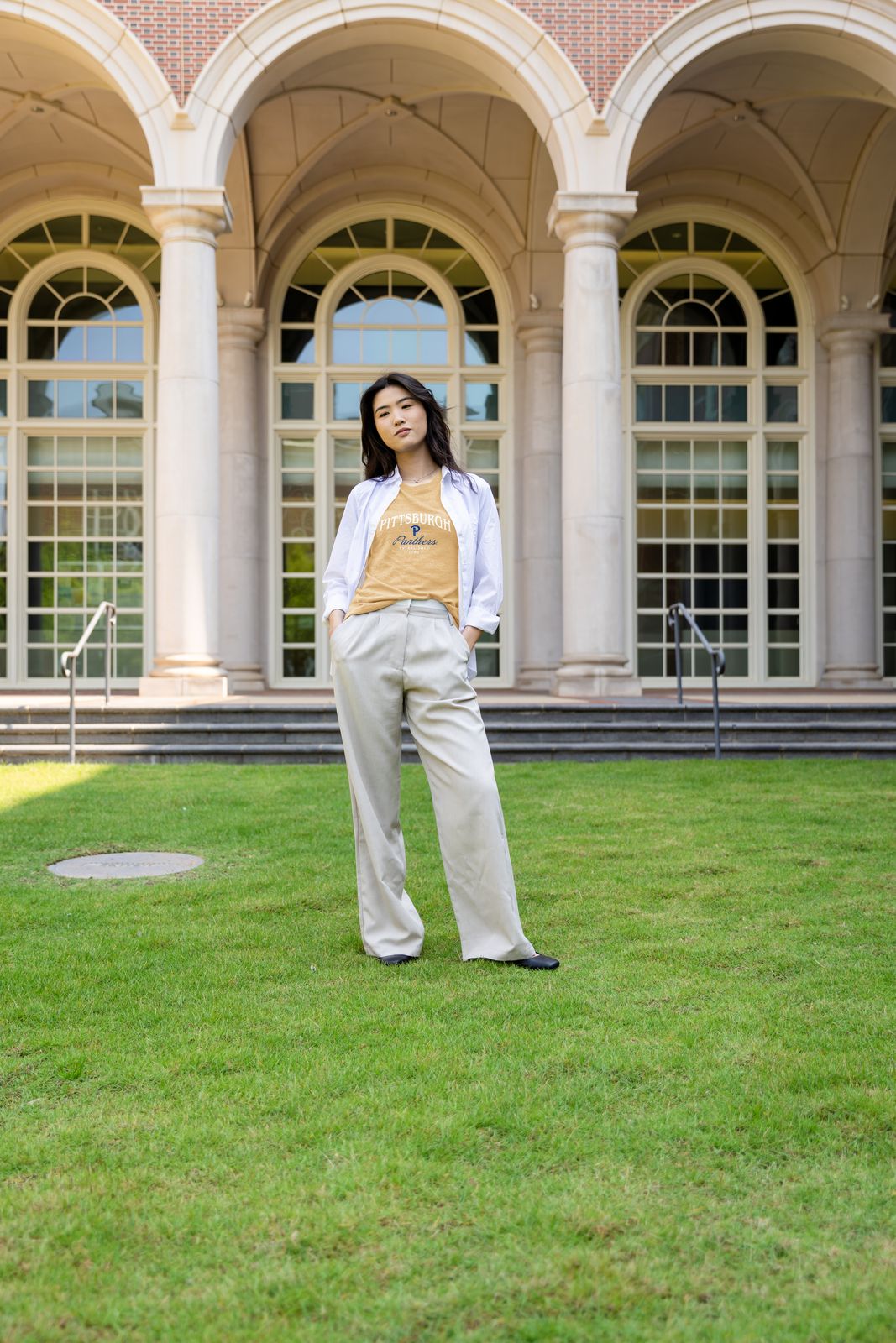 a woman standing in the grass in front of a building