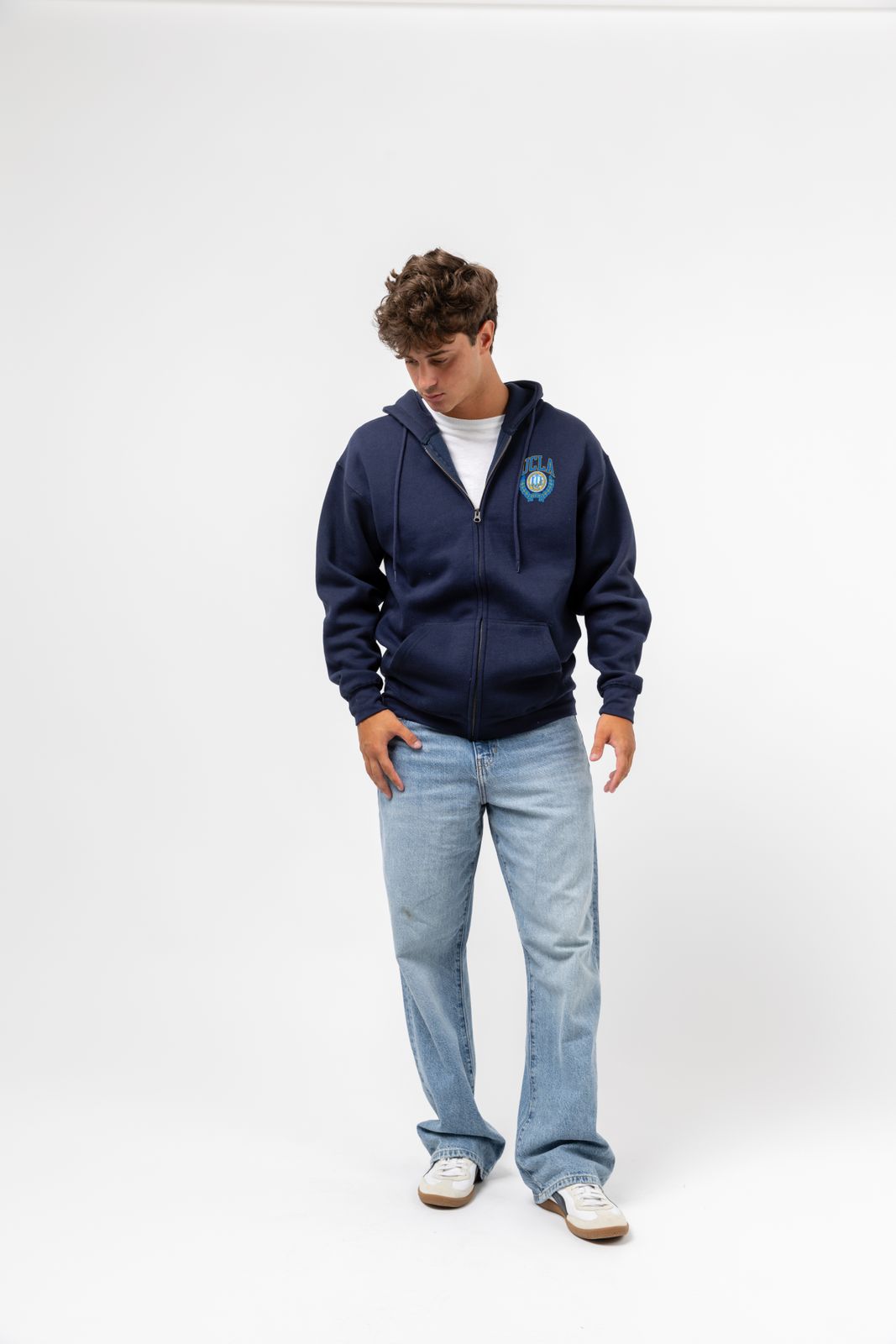 a man in a blue hoodie standing with his hands in his pockets