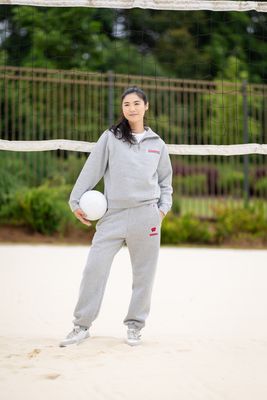 a woman holding a white ball in front of a volleyball net