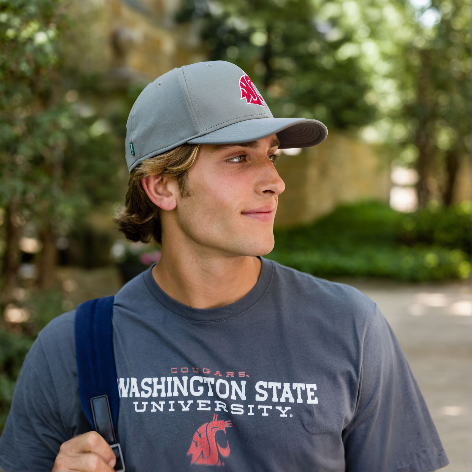 a young man wearing a washington state t - shirt and carrying a backpack