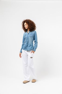 a woman wearing white pants and a denim shirt