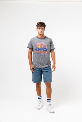 a man in a kansas t - shirt and shorts poses for a picture