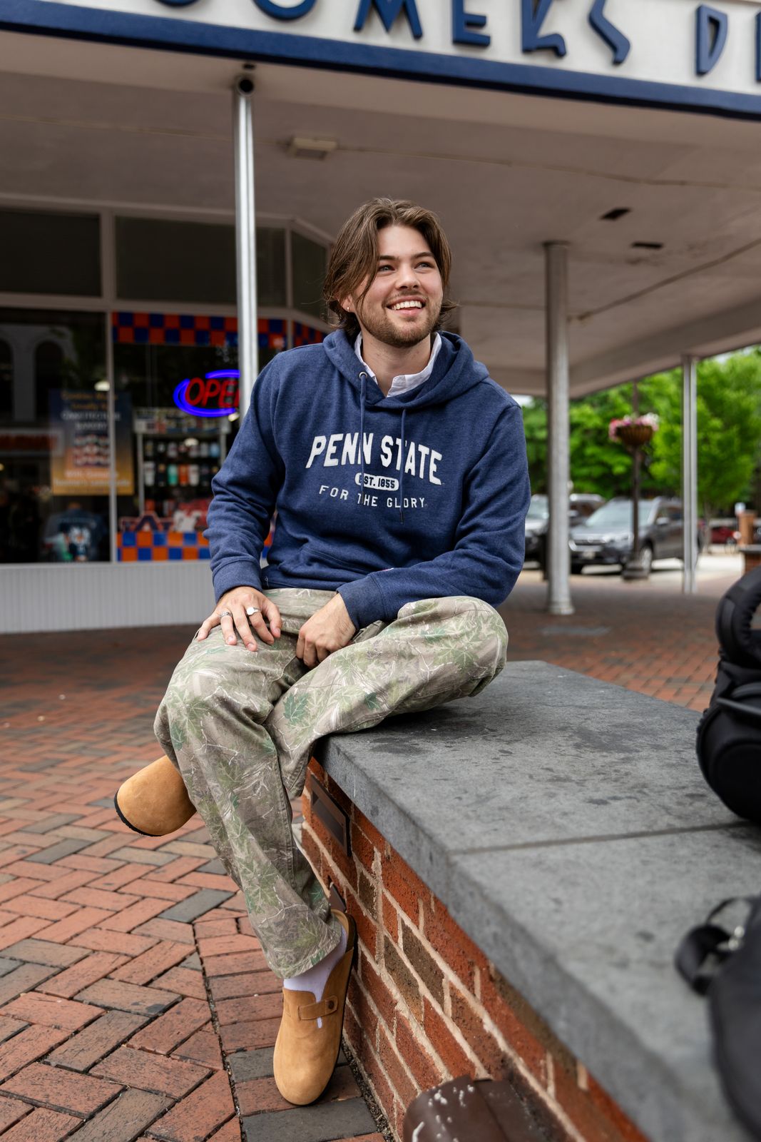 a man sitting on a brick wall in front of a store